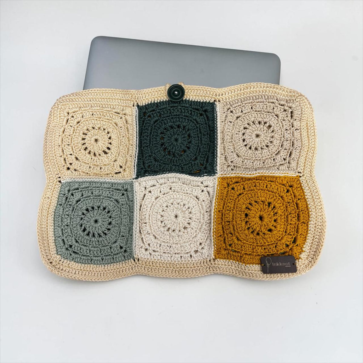 Handmade crochet laptop sleeve in beige, black, grey, cream and mustard patchwork squares with a button closure